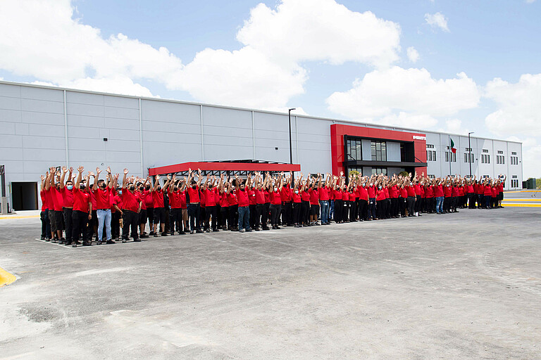 Photo: Hilti: Many people raising their hands outside of the factory