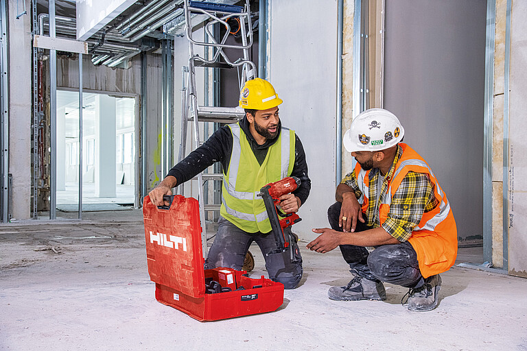Photo: Hilti: Two persons sitting in front of an opened Hilti case