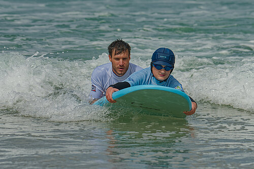 Photo: Hilti: A man and a boy are in the water with a surfboard.