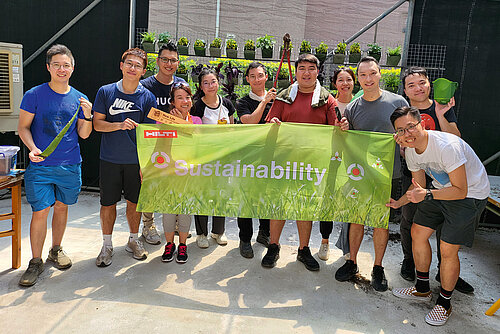 Photo: Hilti: Eleven young people smiling into the camera and holding up a green HILTI sustainabiliry header.