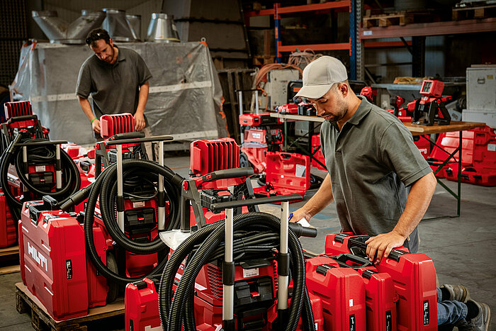 Photo: Hilti: A man with a cappy is checking the delivery of Hilti tool cases in a hall