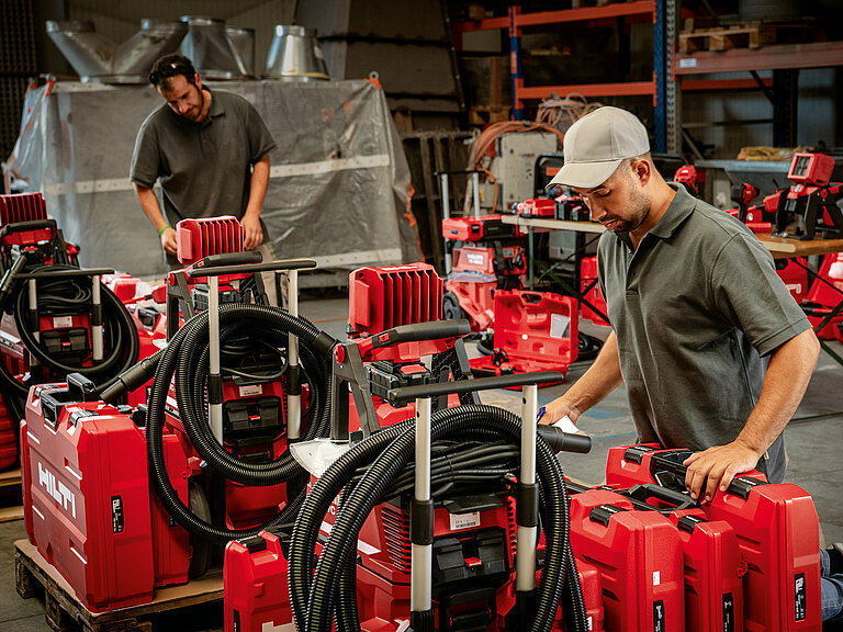 Photo: Hilti: A man with a cappy is checking the delivery of Hilti tool cases in a hall
