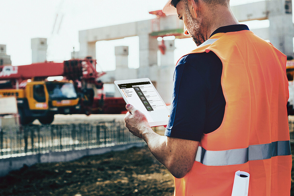 Photo: Hilti: A man with a green veste is sitting at his desk working on his computer