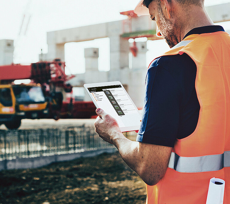 Photo: Hilti: A man with a green veste is sitting at his desk working on his computer