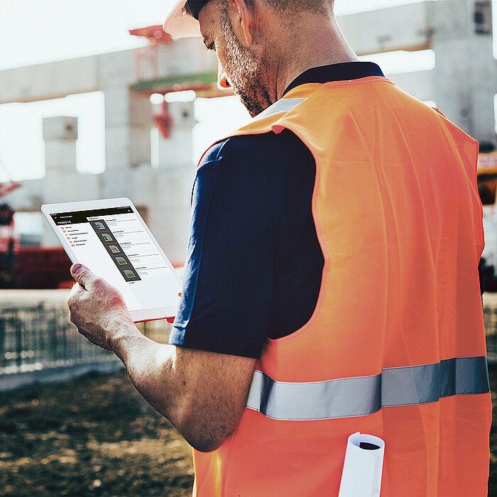 Photo: Hilti: A man with a green veste is sitting at his desk working on his computer