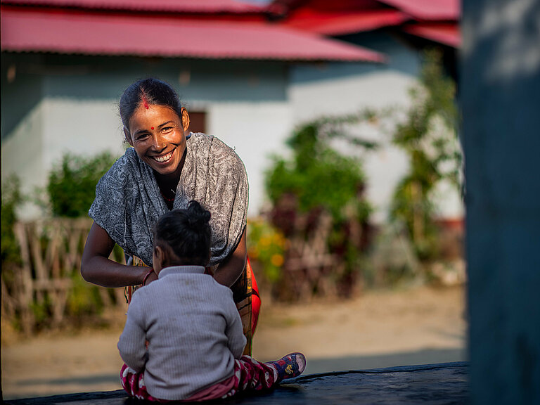 Photo: Hilti: A woman with a child sitting outside, the woman is looking in the camera smiling