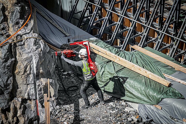 Photo: Hilti: A man on a construction site wearing a Hilti tool on his back and working with another Hilti tool in his hands