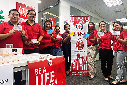 A group of young people posing in front of an exibition stand for the philippine red cross.