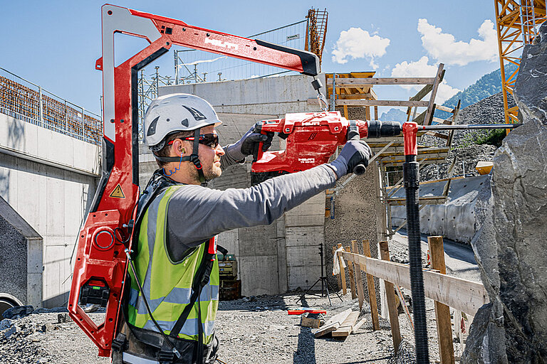 Photo: Hilti: A man on a construction site wearing a Hilti tool on his back and working with another Hilti tool in his hands