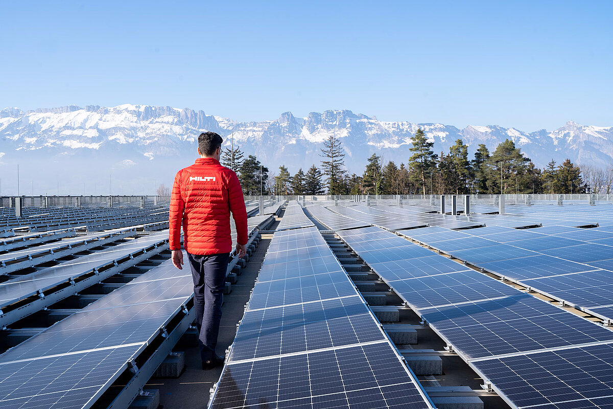 Photo: Hilti: Man from the back walking through solar panels, in the back there are mountains