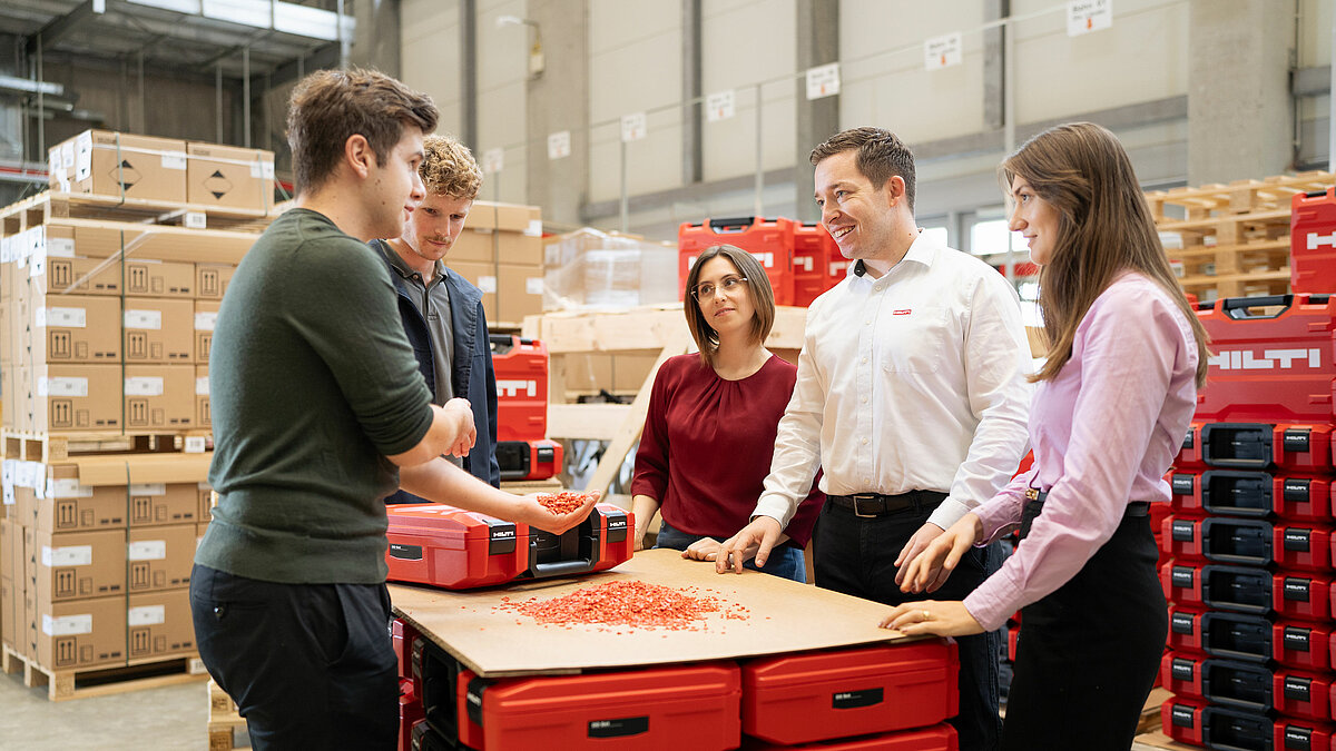 Photo: Hilti: A team surrounded by Hilti Tool cases, one of them hold recycling material in his hand