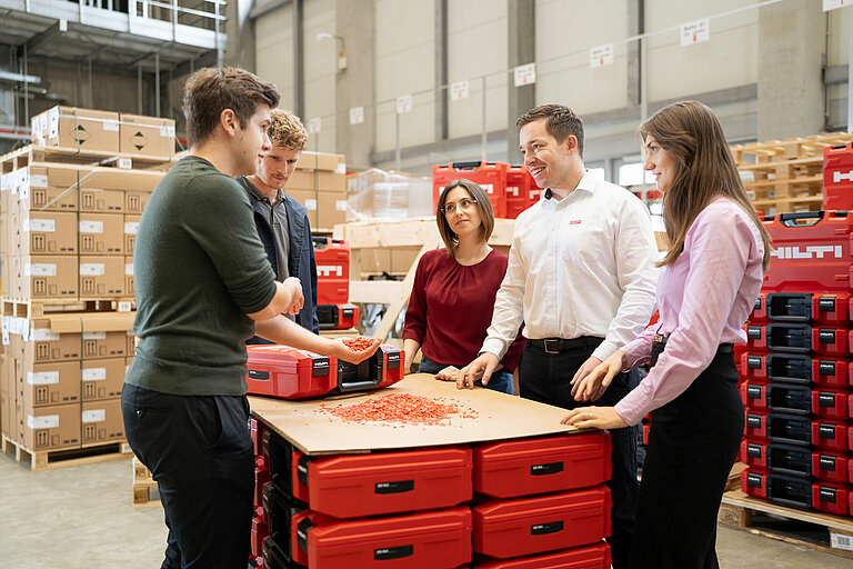 Photo: Hilti: A team surrounded by Hilti Tool cases, one of them hold recycling material in his hand