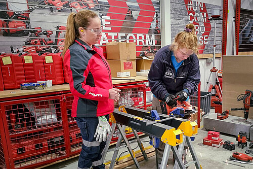 During the Women in Construction program, a female Hilti employee instructs another woman on how to use a tool.