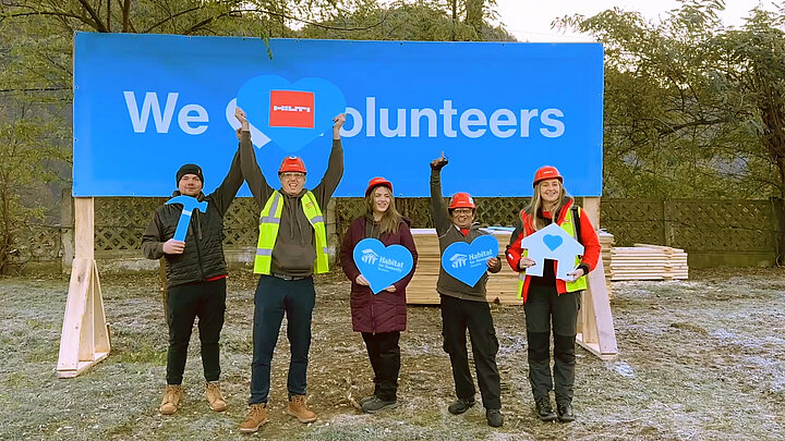 Group photo of volunteers in front of a poster with the words “We love volunteers” 