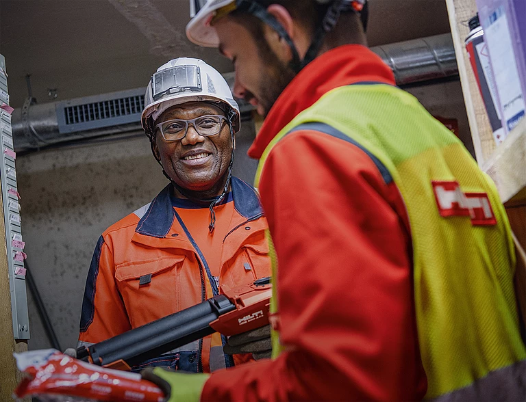 Two workers, one of them holding a dispensing device