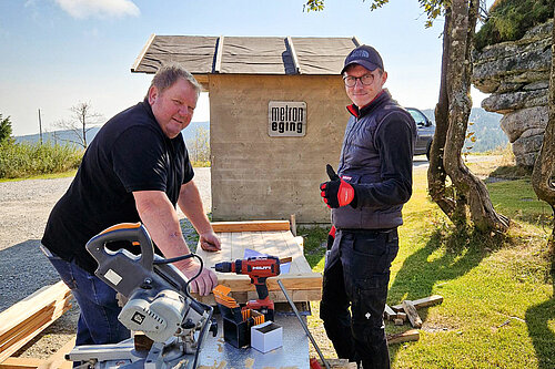 Two volunteers work on a wooden panel with Hilti tools to renovate the Dreisessel Mountain Hut in the Bavarian Forest. 