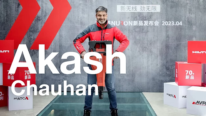 Akash Chauhan in red Hilti work clothes with hands on his hips. 