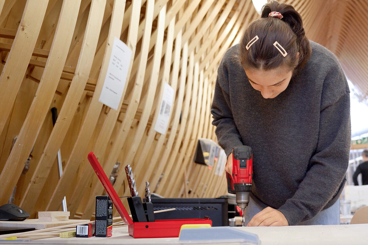 Woman working with a Hilti tool on a workbench.
