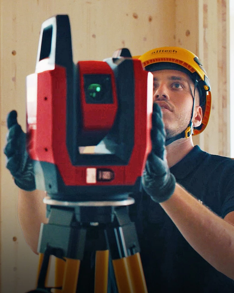 Two workers from Alltech Installation AG wearing yellow safety helmets and blue shirts, working together on the new construction of the Arlesheim Clinic near Basel.
