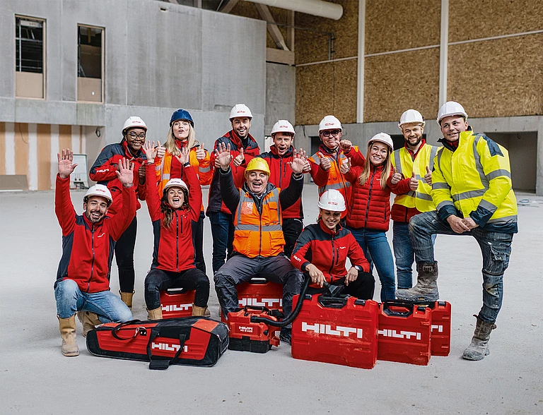 Happy Hilti workers in construction workwear surrounded by Hilti tools and cases